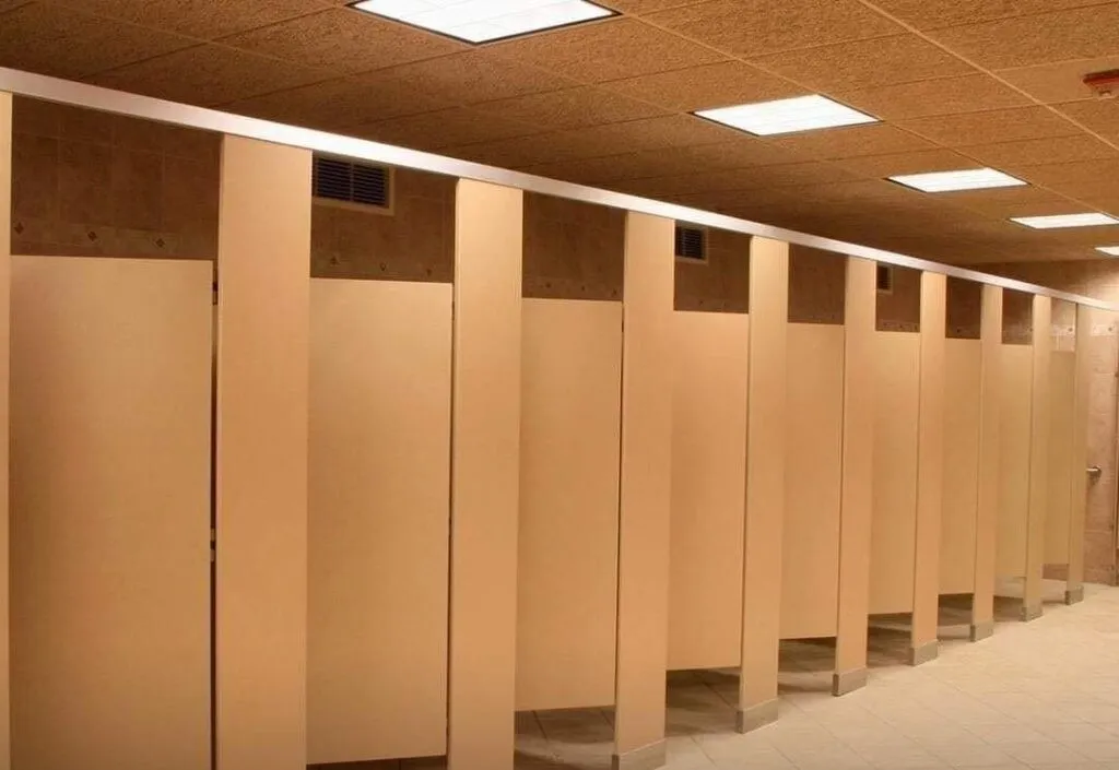 Why do public bathroom doors not reach the floor?